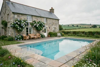 Gîte en pierre bretonne avec piscine turquoise entouré de verdure typique de la Bretagne